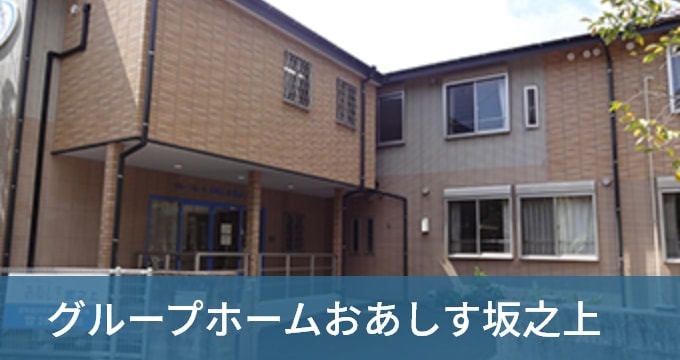 介護施設の建物外観。ベージュ色のレンガ造りで、玄関ポーチと複数の窓が見える。